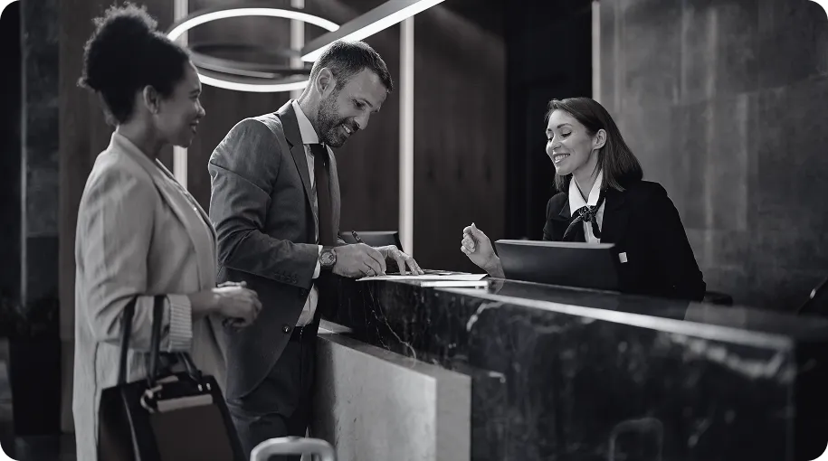Two people checking in at a hotel desk